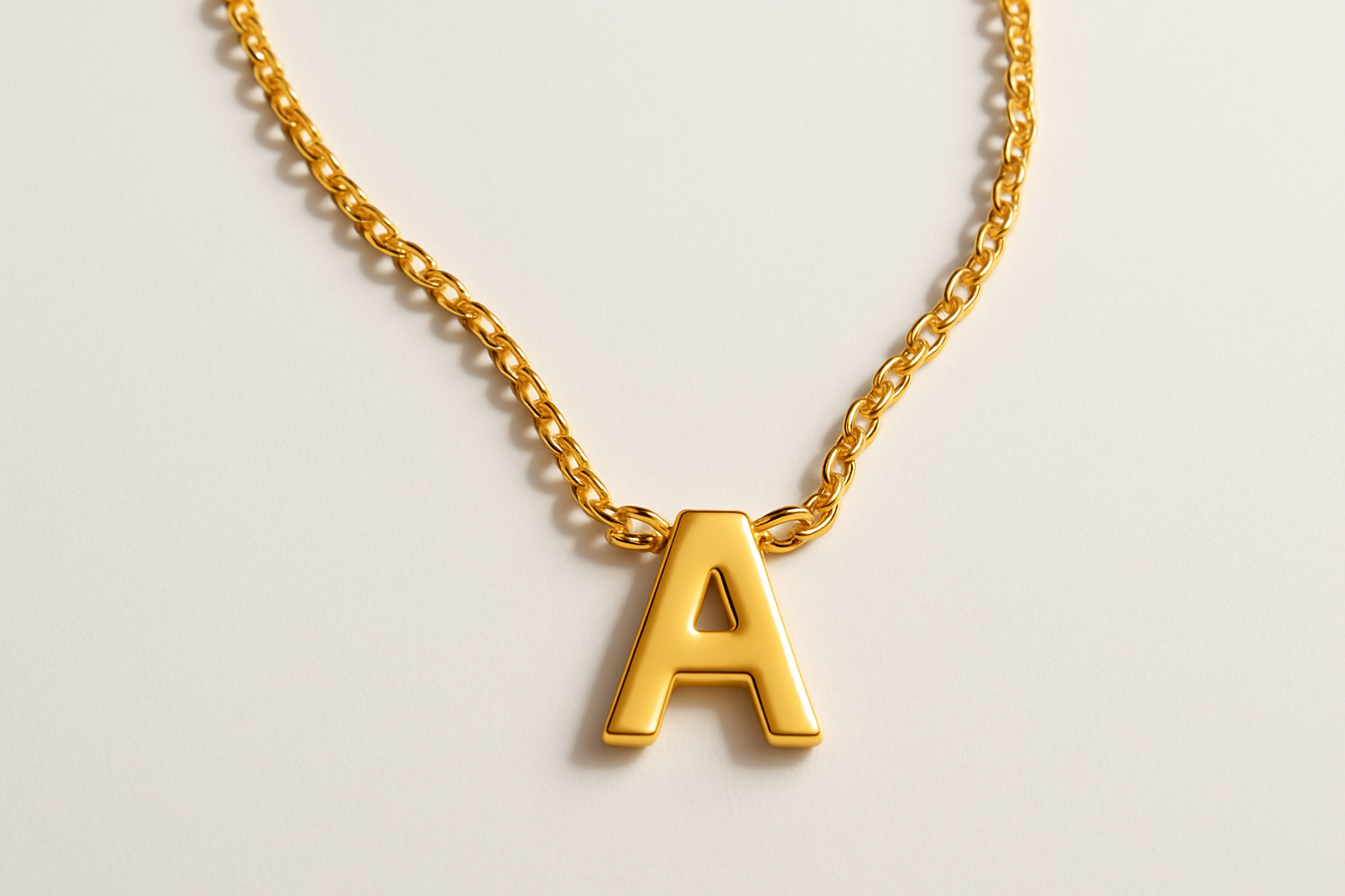 Professional flatlay of gold necklace with letter A pendant