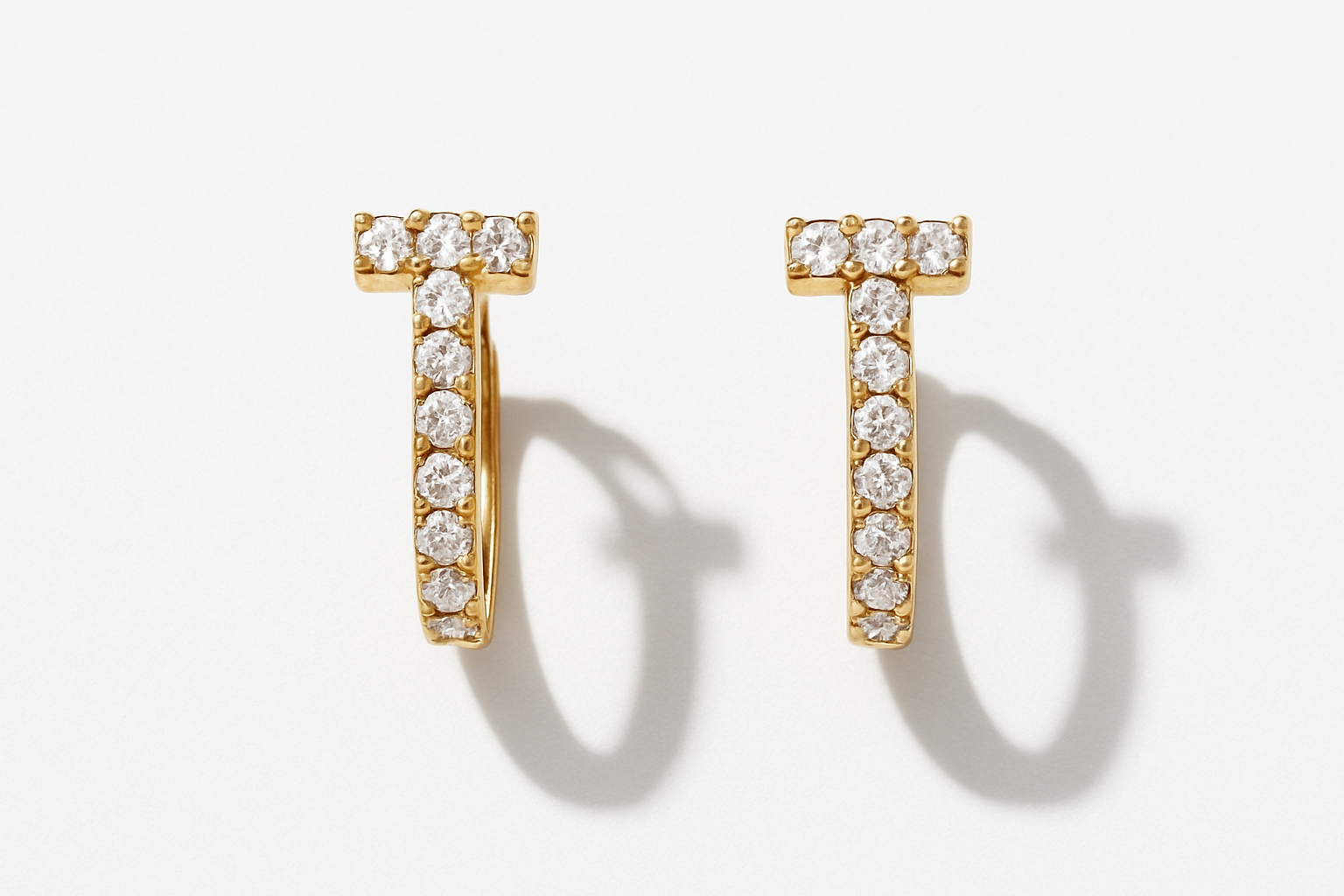 Professional studio flatlay of T-shaped crystal huggie earrings